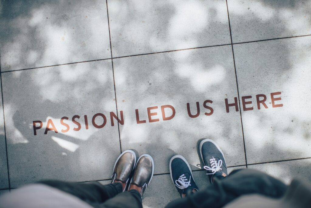 情熱が導いた場所——英語学習のゴールの象徴として PASSION LED US HEREと書かれたゴール地点に立つ2人の足元