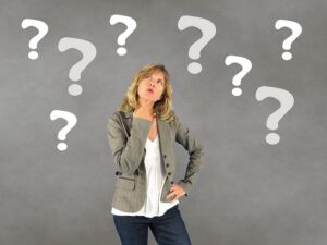 クエスチョンマークに囲まれて悩む女性のイメージ（英単語の覚え方に迷う様子）