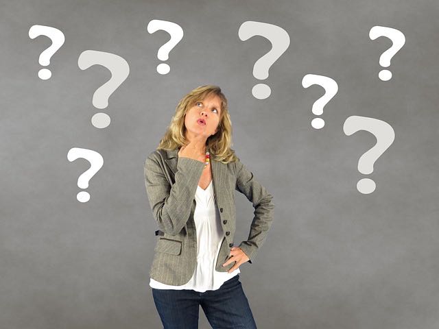 クエスチョンマークに囲まれて悩む女性のイメージ（英単語の覚え方に迷う様子）
