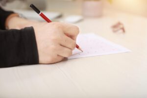 TOEIC模試の解答用紙に赤いペンでマークする手元の様子。集中した試験演習シーン。