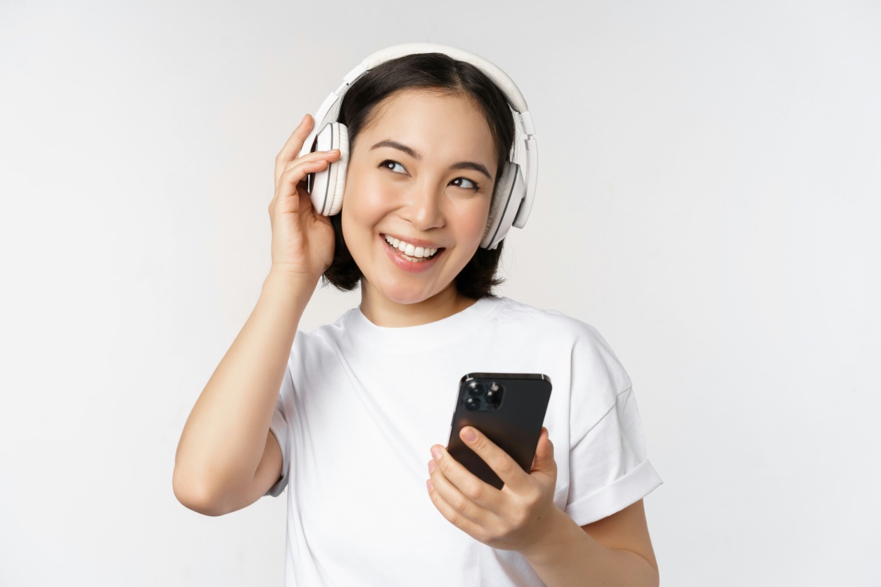 ヘッドホンで英語を聴きながら笑顔で学習する女性