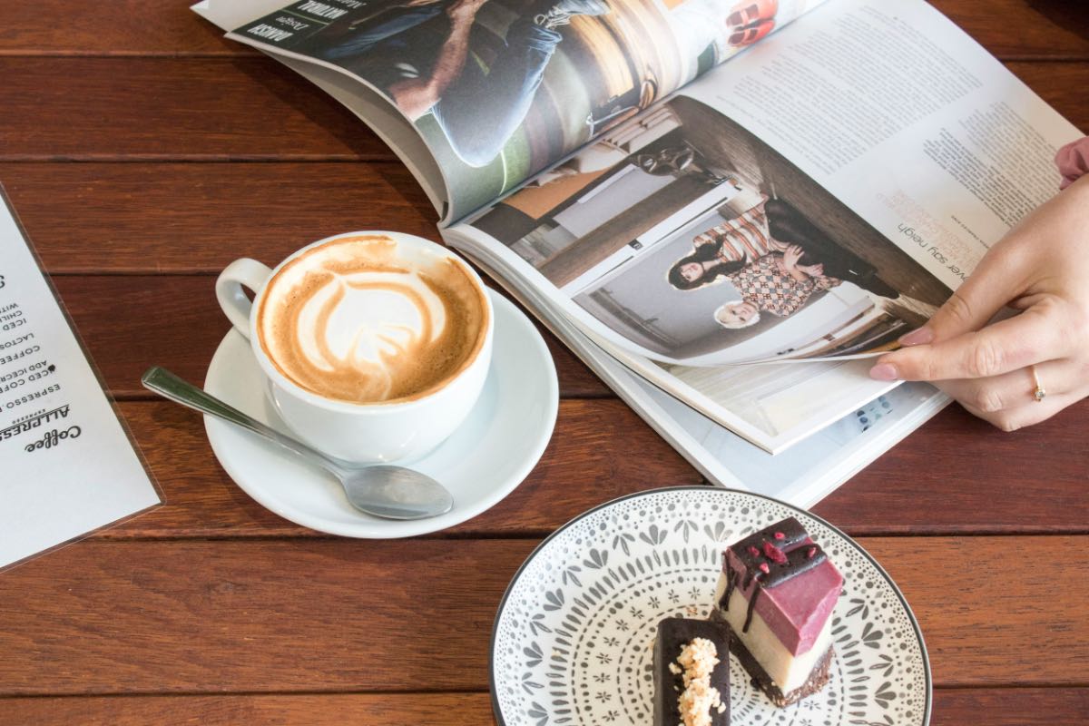カフェでコーヒーを飲みながら英文ニュースや雑誌を読む様子
