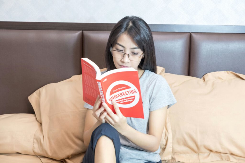 ベッドで本を読みながら落ち着いて学ぶ女性。英語学習の快読ゾーンを象徴する写真。