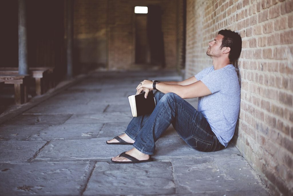 英語をやり直したいと考えながら本を持って座り込む社会人男性