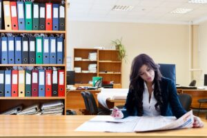 オフィスで英文書類を読みながらペンを持つ女性ビジネスパーソン