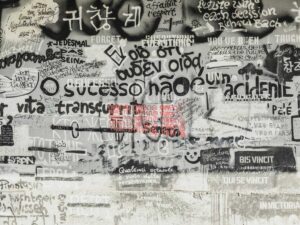 多言語の文字が重なり合う壁の写真|言葉が持つ「記号」と「イミ」の多様性を象徴する一枚