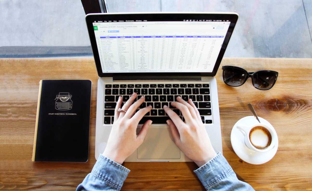 カフェでノートPCの表計算データに向き合う手元|AIで仕事の効率化を図るイメージ