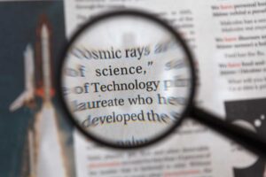 虫眼鏡で新聞記事の英文を拡大して読み込むイメージ|英語の難しさを可視化する挑戦